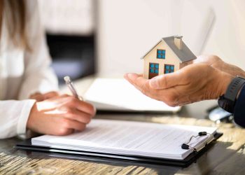 Woman signing a form for a property investment loan application.