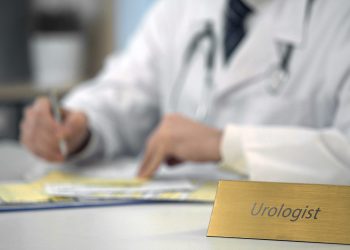 Urologist consulting patients online using laptop, typing monthly report, health