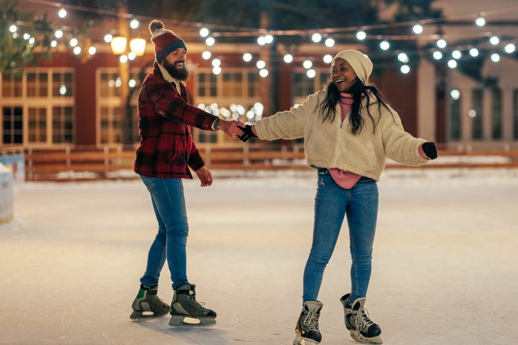 A young couple is on a winter holiday ice skating in the skating ring alone.