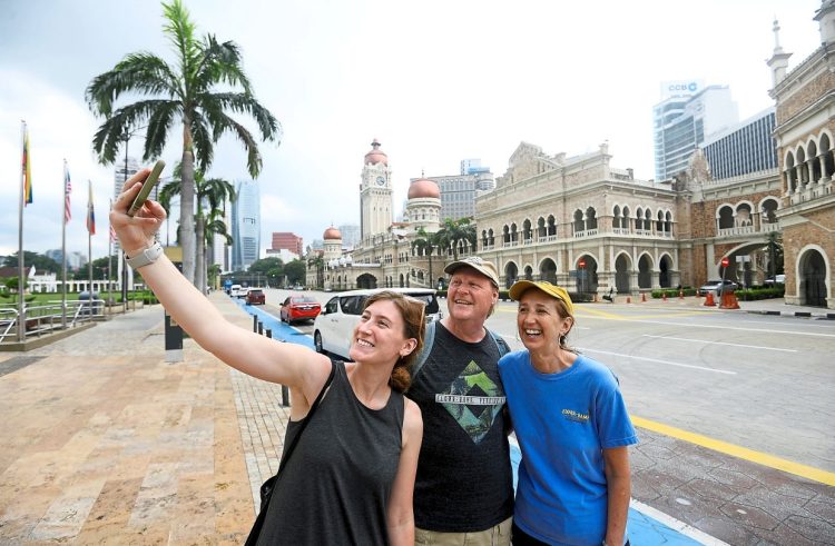 from L-R, Hannah Lins, Dennis Lins and Lori Lins from USA wefie with the backaground of Malaysian iconic building Sultan Abdul Samad in Kuala Lumpur
(11/6/2022). —AZHAR MAHFOF/The Star